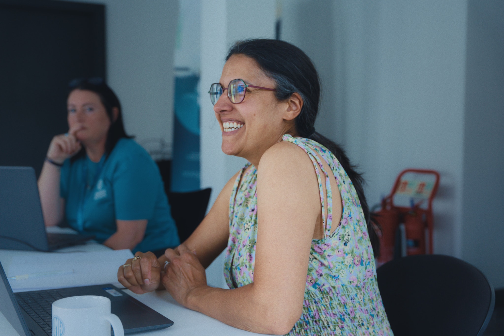 Unmasked staff smiling and talking together during a workshop-style meeting